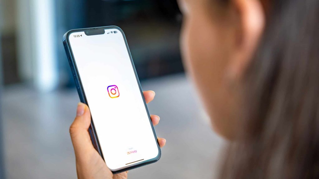 Moça jovem abrindo o Instagram no celular